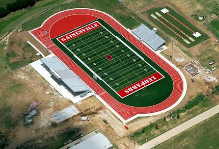 Aerial view showcasing a football field surrounded by a stadium, highlighting the vibrant green turf and seating areas.